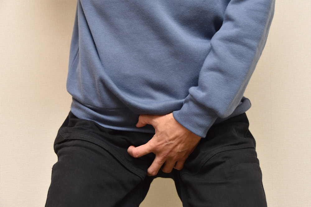 股間を押さえる男性